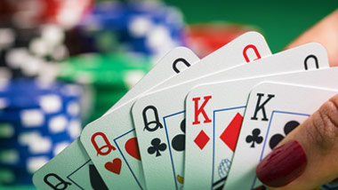 close up of a poker hand with blurred chips in the background